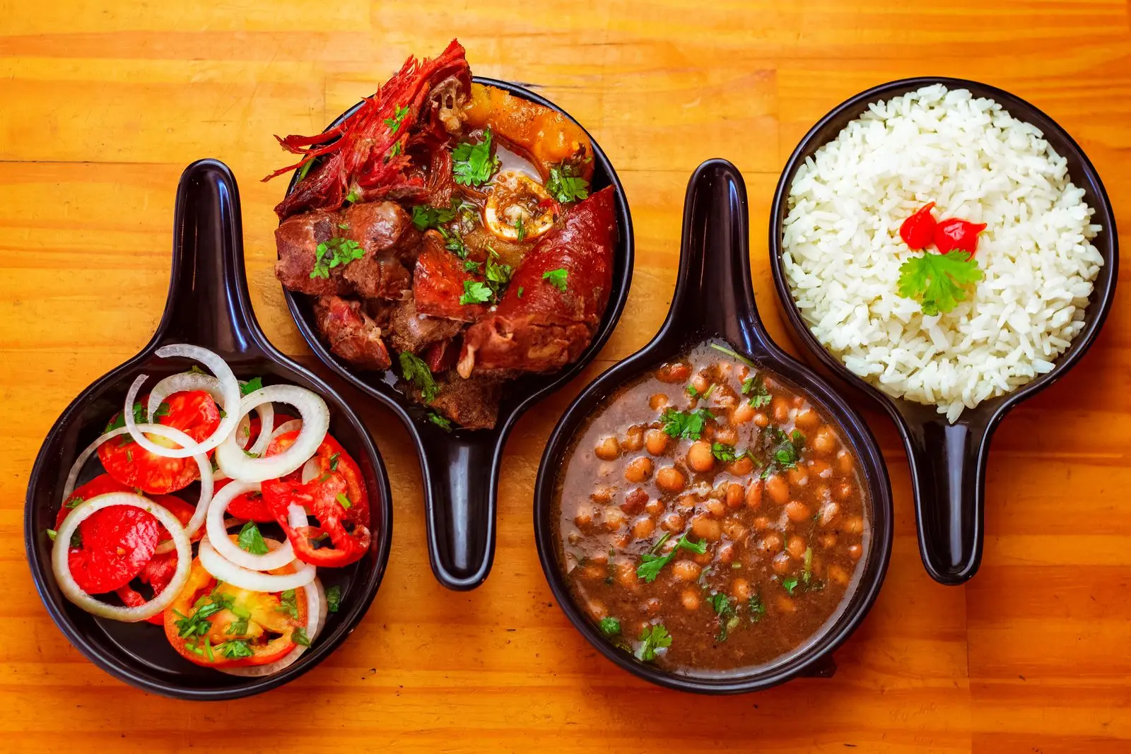 Prato feito em travessas: carne, feijão, arroz branco e vinagrete